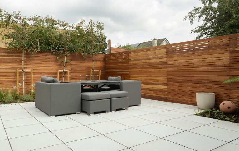 Überdachte Terrasse Überdachte Terrasse mit Glaswänden an einem modernen Gebäude, umgeben von Rasen.