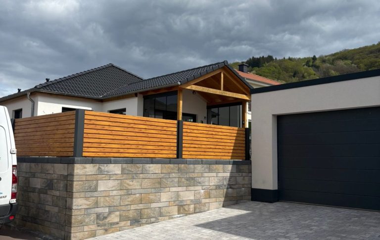 Überdachte Terrasse Überdachte Terrasse mit Glaswänden an einem modernen Gebäude, umgeben von Rasen.