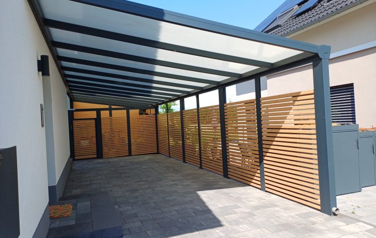 Überdachte Terrasse Überdachte Terrasse mit Glaswänden an einem modernen Gebäude, umgeben von Rasen.